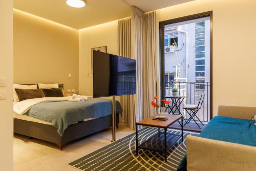 a bedroom with a bed and a tv and a balcony at Herzl Luxury Hotel By Nimizz in Tel Aviv