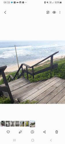 a wooden bench sitting on a boardwalk near the beach at Coastal Cottage in Klein Brak Rivier