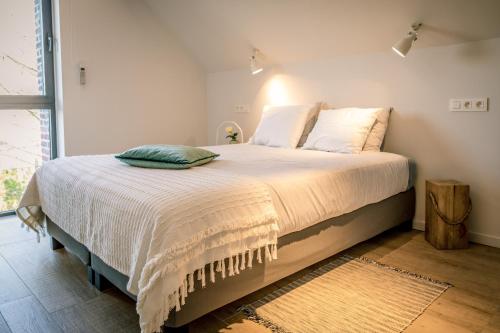 a bedroom with a large bed with white sheets at B&B De Woestijn in Roosdaal