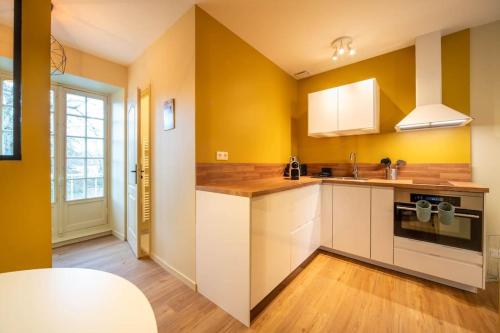 une cuisine avec des murs jaunes et des armoires blanches dans l'établissement Château de Dracy - La Pétillante, à Dracy-le-Fort