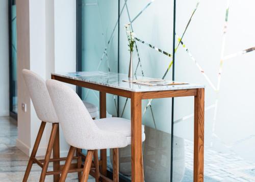 a glass table with two white chairs and a table at Urban by CityBlue Hotel, Dar es Salaam in Dar es Salaam