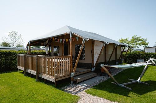 a yurt with a porch and a hammock in a yard at Vakantiepark de Molenhoek in Kamperland