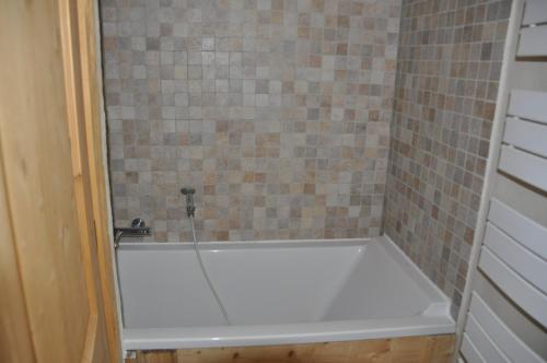 La salle de bains carrelée est pourvue d'une baignoire blanche. dans l'établissement Cortina - 21 - Appart belle vue - 8 pers, à Les Deux Alpes