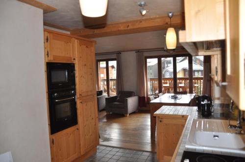 une cuisine avec des placards en bois et un salon dans l'établissement Cortina - 21 - Appart belle vue - 8 pers, à Les Deux Alpes