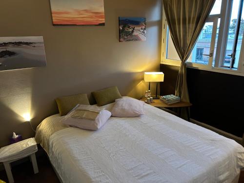 1 dormitorio con cama con almohadas y ventana en A L'OMBRE DE LA TOUR EIFFEL AU BORD DE LA SEINE, en París