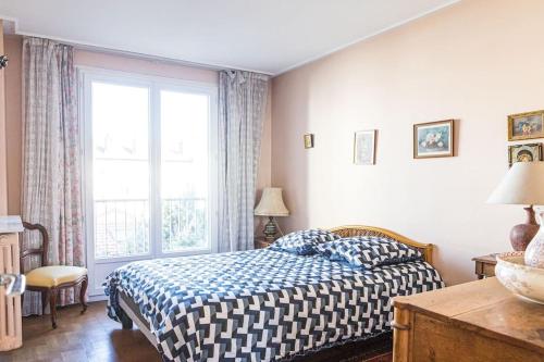 une chambre avec un lit et une grande fenêtre dans l'établissement L'ESCUDIER Appartement calme proche Rolland Garros avec vue panoramique et parking, à Boulogne-Billancourt