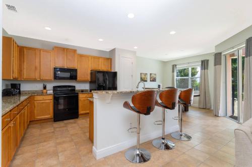 eine Küche mit Holzschränken und Barhockern in der Unterkunft Top Villas - Encore Resort 1528 in Orlando