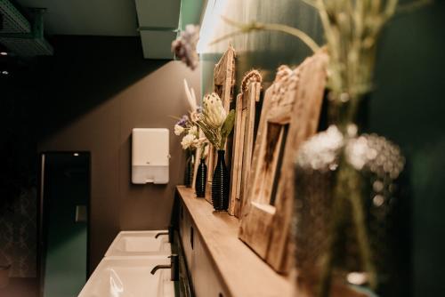 a bathroom with vases of flowers and pictures on a counter at Capsule Hotel - Lucerne Old Town in Luzern