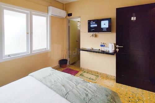 1 dormitorio con 1 cama, puerta y TV en Arwana Inn Lampung RedPartner en Bandar Lampung