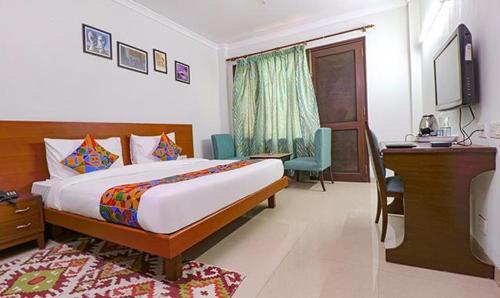 a bedroom with a bed and a desk and a television at Tipsyy Inn Suites 020 in Gurgaon