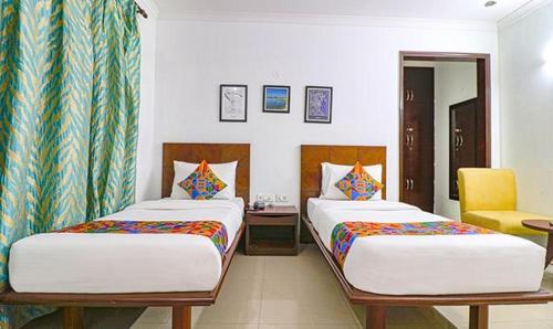 - une chambre avec deux lits et une chaise jaune dans l'établissement TIPSYY INN 020, à Gurgaon