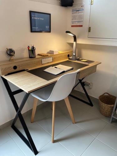 einen Schreibtisch mit einem Stuhl und einem Computermonitor in der Unterkunft A l'Abri du Temps in Châteaudun