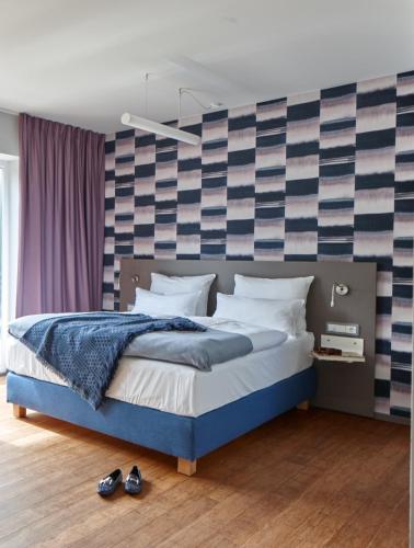 a bedroom with a blue bed with a striped wall at Just Eleven in Sankt Peter-Ording