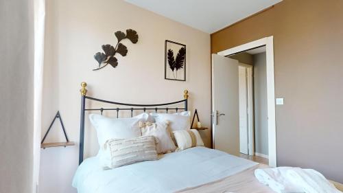 une chambre avec un lit avec des draps blancs et des oreillers dans l'établissement L'alsacienne, à Colmar