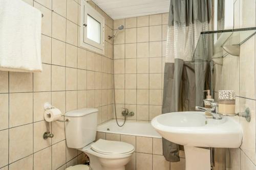 ein weißes Bad mit einem WC und einem Waschbecken in der Unterkunft Zante's Azure Nest - Serene Summer Getaway in Ambelókipoi