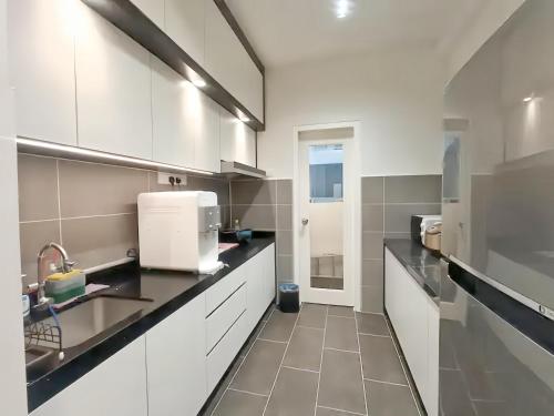 a kitchen with white cabinets and a sink at The Cove Hillside Residence Ipoh in Ipoh