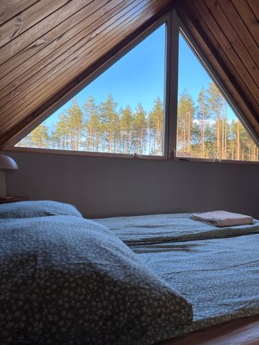 two beds in a room with a large window at Bliżej Lasu in Śliwice