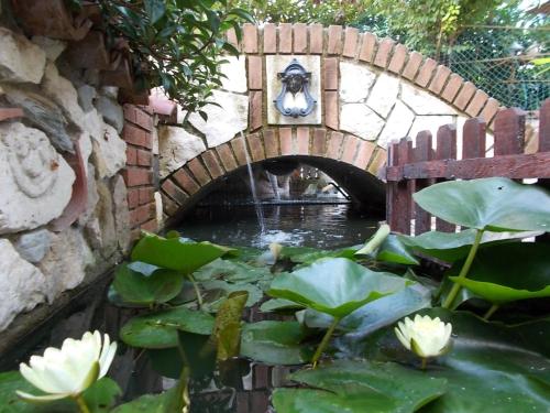 a small brick bridge over a pond with lilies at B&B Il Giardino Acquatico in Coppito