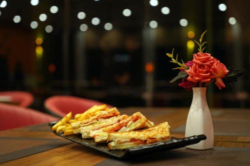 a plate of food on a table with a vase of roses at The Neeraj Naturecure On Ganga in Rishīkesh