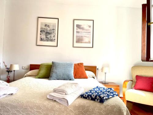 a bedroom with a bed with colorful pillows on it at Mundaka bihotzean con parking gratuito in Mundaka