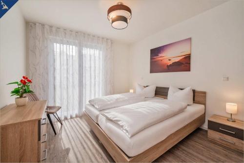 a white bedroom with a large bed and a desk at An der Haffküste Klippenblick in Zirchow