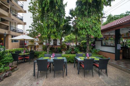 an outdoor patio with tables and chairs and trees at Stable Lodge - SHA Certified in Bangkok