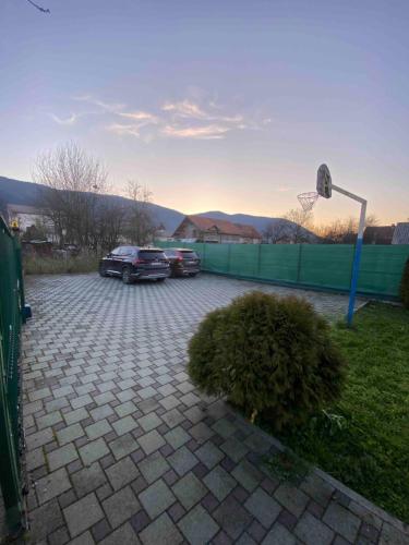 Dois carros estacionados num parque de estacionamento com um cesto de basquetebol. em Villa Green em Sarajevo