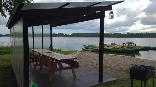 a pavilion with a picnic table and a bench next to a lake at Jaundzirnieki in Valdemārpils