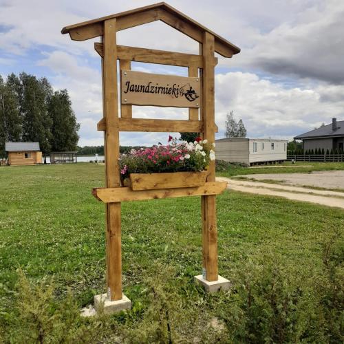 a wooden sign with flowers in a field at Jaundzirnieki in Valdemārpils