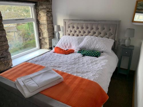 a bed with two stuffed animals on it with a window at Bear Pit Cottage in Hayfield