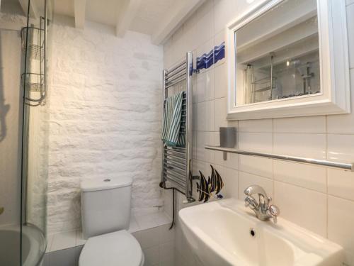 a white bathroom with a toilet and a sink at Bear Pit Cottage in Hayfield
