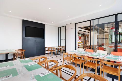 a restaurant with tables and chairs and a flat screen tv at ibis Jakarta Raden Saleh in Jakarta