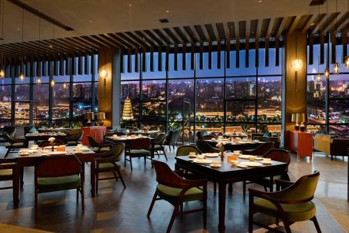 a restaurant with tables and chairs and a view of a city at Mehood Elegant Hotel Xi'an Big Wild Goose Pagoda Tang Dynasty City in Xi'an