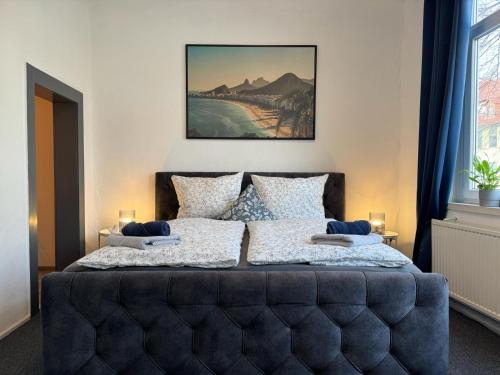 Schlafzimmer mit einem Bett mit einem blauen getufteten Kopfteil in der Unterkunft Apartment Goethe in der Göttinger Innenstadt in Göttingen
