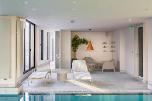 a house with a swimming pool and two chairs and a table at Euforia Retreat and Spa in Eforie Nord