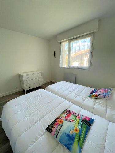une chambre avec deux lits blancs et une fenêtre dans l'établissement Réf 558 Seignosse océan, bel appartement classé 1 étoile VUE MER , proche plage et centre, 4 personnes, à Seignosse