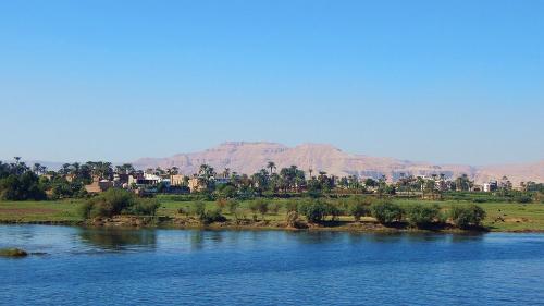 a town on the banks of a river with mountains in the background at luxo bankr west in Luxor