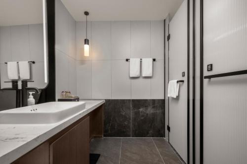 黃山的住宿－美豪酒店黄山高铁北站店，白色的浴室设有水槽和淋浴。