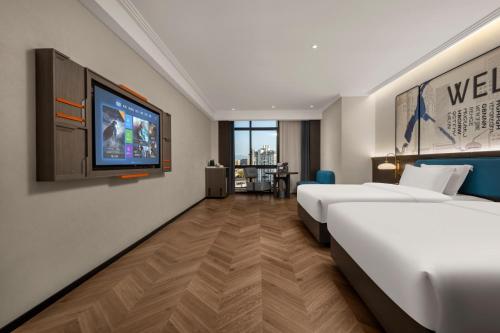a hotel room with two beds and a flat screen tv at Mehood Hotel Huangshan High-Speed North Station in Huangshan