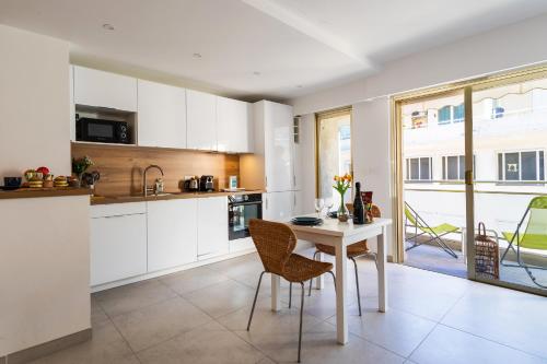 une cuisine avec des armoires blanches et une table et des chaises dans l'établissement OMAN1 Magnifique et modern deux pieces, à Cannes