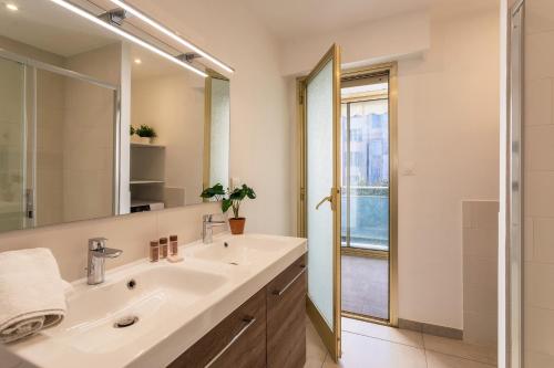 une salle de bain avec un lavabo et un miroir dans l'établissement OMAN1 Magnifique et modern deux pieces, à Cannes