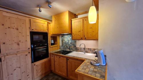 Elle comprend une petite cuisine avec des placards en bois et un évier. dans l'établissement Cortina - 34 - Appart vue montagne - 8 pers, à Les Deux Alpes