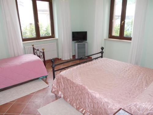 a bedroom with two beds and a tv and windows at B&B Il Giardino Acquatico in Coppito