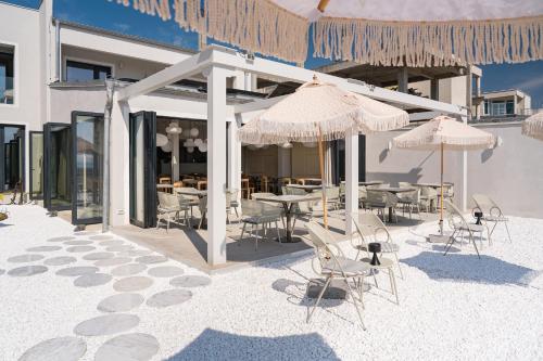 a patio with tables and chairs and umbrellas at Euforia Retreat and Spa in Eforie Nord