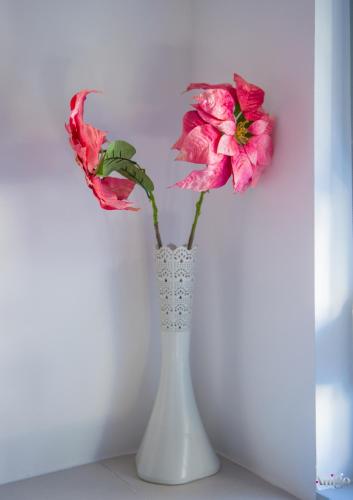 a white vase with two pink flowers in it at Apartment Novax - Free Parking in Mostar