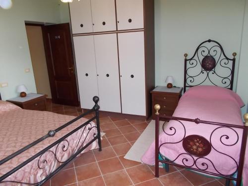 1 dormitorio con 1 cama con sábanas rosas y armarios blancos en B&B Il Giardino Acquatico en Coppito