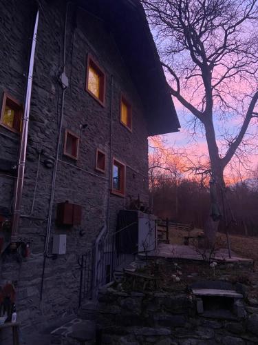 um edifício de pedra com uma árvore em frente em Chalet Epinel em Villaret