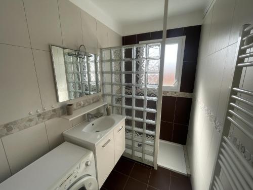 une salle de bain blanche avec un lavabo et un miroir dans l'établissement LS05022 Le Petit Ampère 700m de la plage, à Les Sables-dʼOlonne