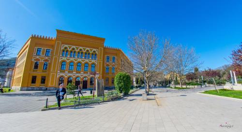 a woman standing in front of a yellow building at Apartment Novax - Free Parking in Mostar