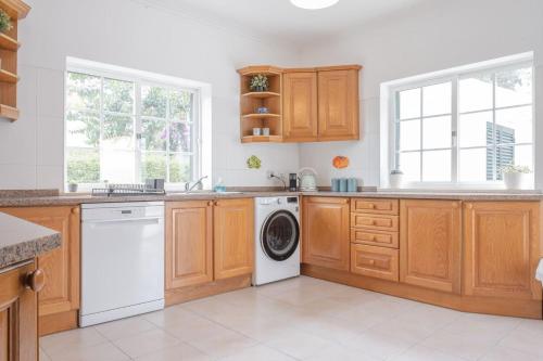 a kitchen with wooden cabinets and a washer and dryer at Nini Beach House in Aroeira